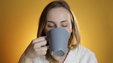 Sarı bir arka plan üzerinde sıcak kahve ile güzel ve genç birbayan