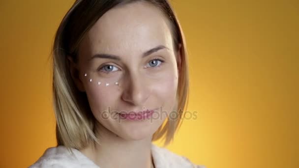 Beau modèle mettant crème visage sur fond jaune — Video