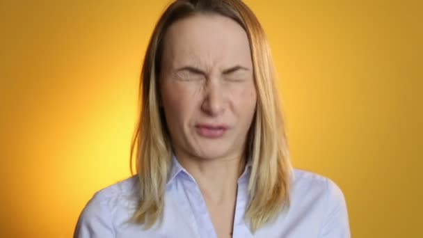Jonge vrouw niezen tegen op een gele achtergrond — Stockvideo