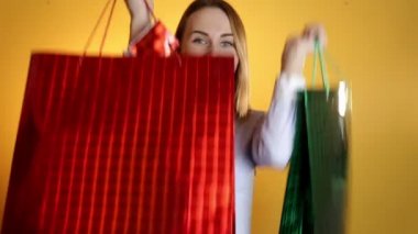 Kadın mutlu gülümseyen holding sarı bir arka plan üzerinde izole poşetler alışveriş. Güzel taze genç yarış Asya Kafkas kadın modeli karışık