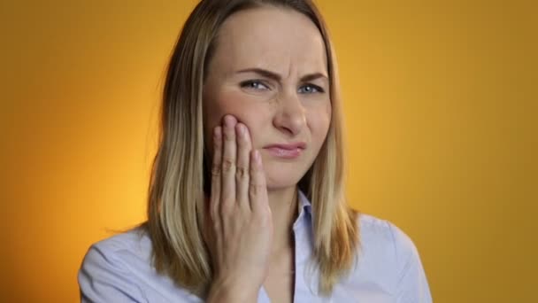 Verärgerte Frau mit Zahnschmerzen vor gelbem Hintergrund — Stockvideo
