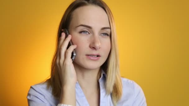 Hermosa mujer joven hablando en el teléfono móvil sobre fondo amarillo . — Vídeos de Stock