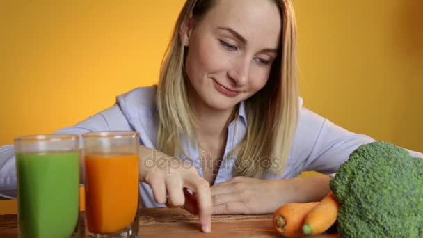 Kobieta przy stole obok soki i warzywa — Wideo stockowe