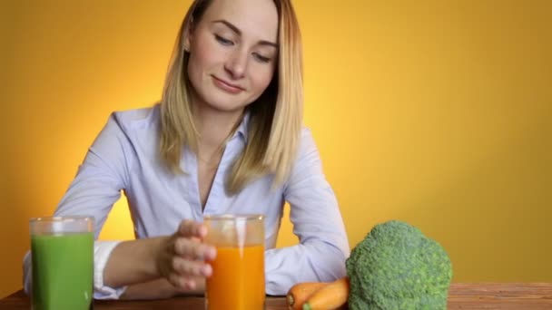 Женщина за столом рядом с соками и овощами — стоковое видео