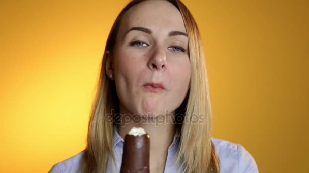 Roztomilá žena jíst zmrzlinu na žlutém podkladu.
