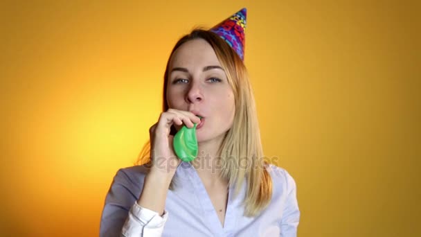 Menina inflando um balão em um fundo amarelo — Vídeo de Stock