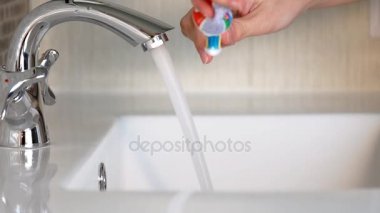 Bir kadın fırçalar ve banyoda dişlerini temizler