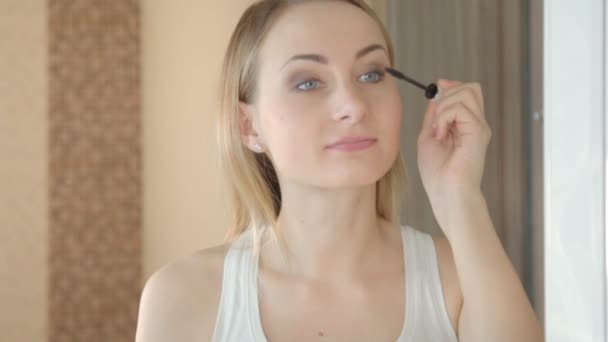 Vacker flicka målar ögonfransar. Kvinna göra make-up närbild — Stockvideo
