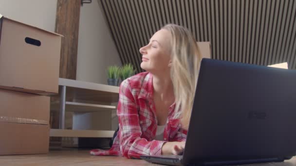 Frau sitzt an ausgepackten Kisten mit Laptop — Stockvideo