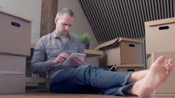 Hombre usando tableta en casa nueva casa después de mudarse . — Vídeos de Stock