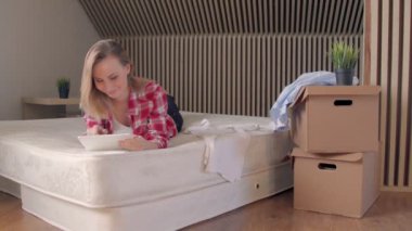 Yeni dairesinde yatak yatan ve tablet üzerinde kullanarak kadın.