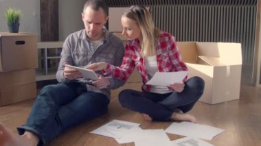 Mutlu genç çift yeni evlerine kutuları açma ve mobilya laptop seçilmesi.