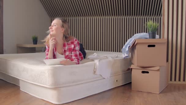 Frau liegt auf Matratze in ihrer neuen Wohnung und benutzt Tablet. — Stockvideo