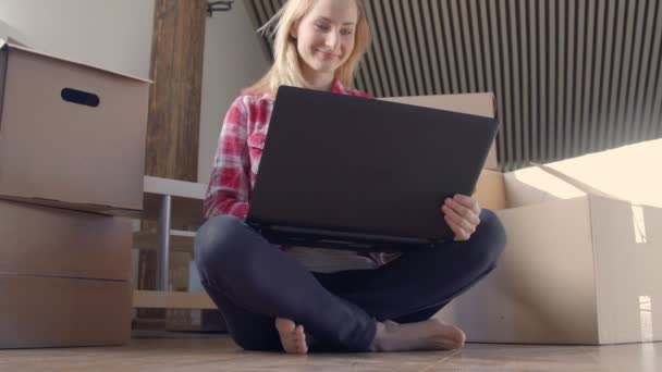 Dolly-Aufnahme einer glücklichen jungen Frau, die in ein neues Haus zieht und ein digitales Tablet benutzt. — Stockvideo