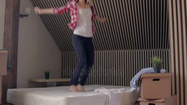 Glückliche blonde schöne Frau springt auf ein Bett — Stockvideo