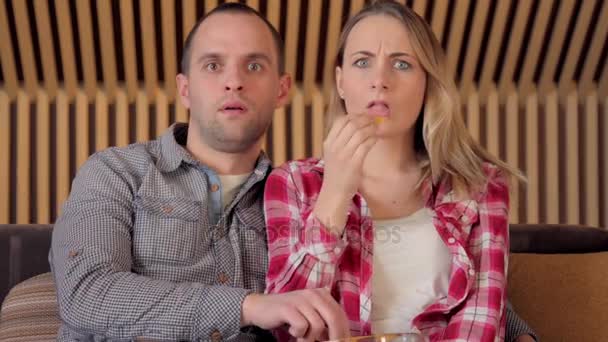 スナックを食べるとテレビで怖い映画を見てのカップルは、ステディカム撮影 — ストック動画