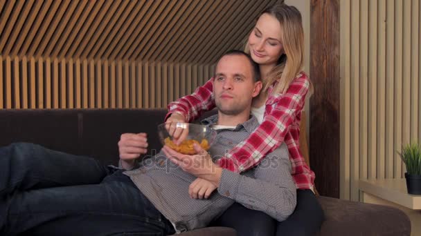 Casal assistindo filme no sofá enquanto come lanches — Vídeo de Stock