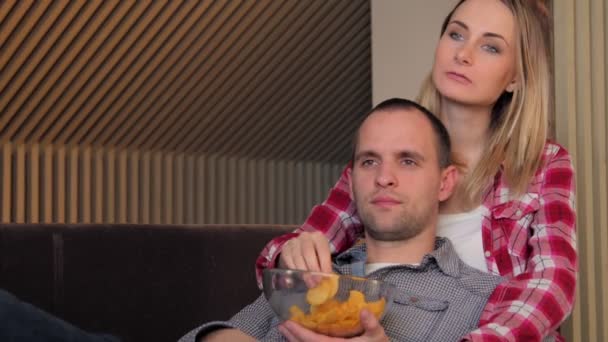 Pareja viendo la película en el sofá mientras come bocadillos — Vídeos de Stock
