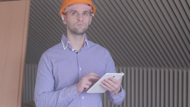 Ein männlicher Architekt blickt auf den Bildschirm seines digitalen Tablets am im Bau befindlichen Gebäude. — Stockvideo