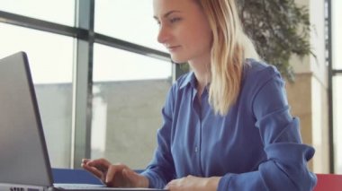 Kafede modern dizüstü bilgisayar üzerinde çalışan genç çekici işkadını