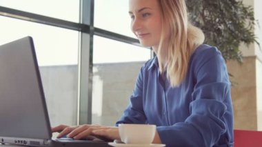 Mutlu genç kadın kahve içme ve tablet bir kafede kullanma