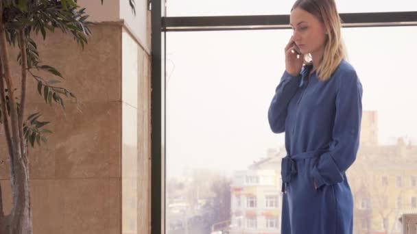 Молодая девушка разговаривает по мобильному телефону в торговом центре — стоковое видео