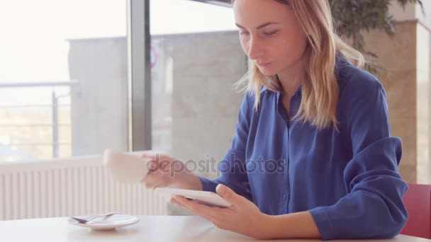 태블릿을 사용 하 고 카페에서 차를 마시는 젊은, 아름 다운 여자 — 비디오