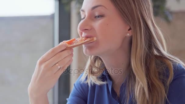 Portrait of young woman eating a slice of pizza — Stock Video