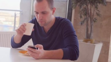 Kafede sandviç yeme smartphone ile genç adam