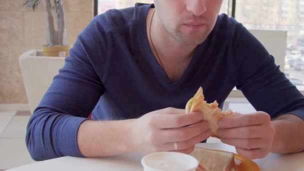 Joven comiendo sándwich, desayuno en el restaurante — Vídeos de Stock