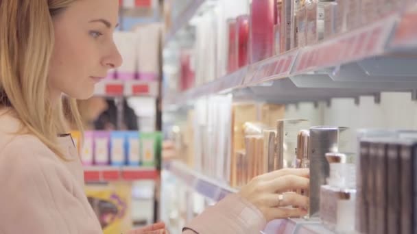 Mladá žena s COP vybírá parfémy v malém obchodě — Stock video