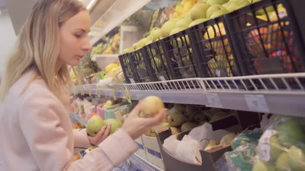 Женщина в супермаркете на овощной полке, покупает продукты, он проверяет продукты — стоковое видео