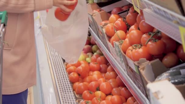 Жінка в супермаркеті вибирає помідори — стокове відео