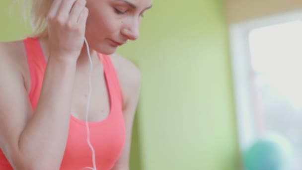 Schöne Fitness-Frau setzt Kopfhörer. — Stockvideo