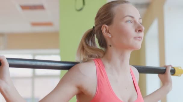 Zijaanzicht portret van een jonge vrouw doet squats in fitness gym — Stockvideo