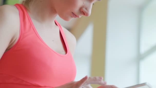 Felice giovane sportiva carina seduta e utilizzando tablet in palestra — Video Stock