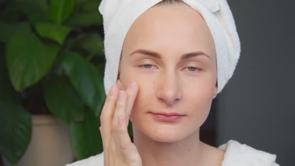 Portrait of beautiful woman applying cream on her face — Stock Video