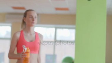 Genç atletik kadın spor minderinde antrenmandan sonra su içiyor..