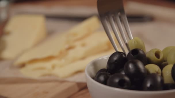 Una forchetta prende un'oliva dal piatto, accanto sul tavolo c'è il formaggio — Video Stock