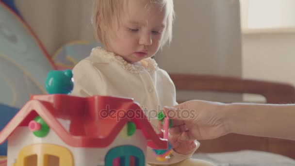 Menina brincando com brinquedos coloridos na cama dos pais  . — Vídeo de Stock