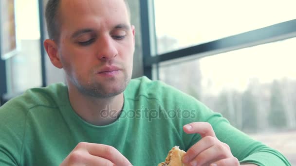 Hombre disfruta comiendo, degustando la deliciosa carne de hamburguesa grande con queso y verduras — Vídeos de Stock