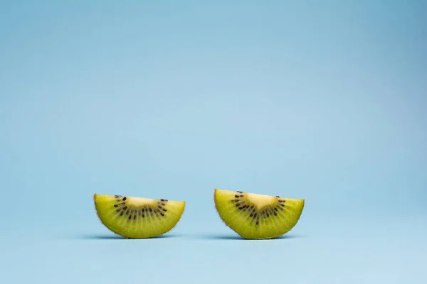 Два ломтика фруктов киви на голубом фоне — стоковое фото