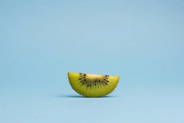 Нарезанные фрукты киви изолированы на голубом фоне, минималистичный поп — стоковое фото