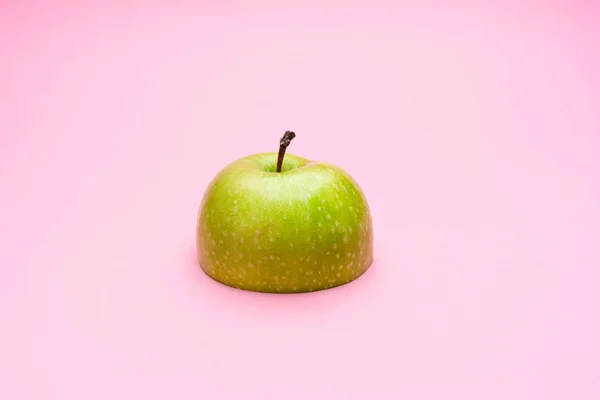 Половина зеленого яблока на розовом фоне . — стоковое фото