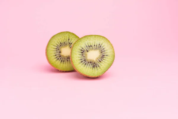 Pastel pembe bir arka plan üzerinde Yarım kesimli kivi.