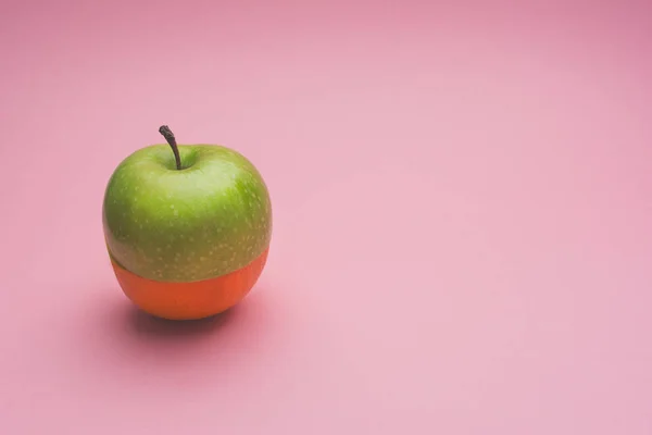 Творческое сочетание половины зеленого яблока и половины апельсина на розовом фоне . — стоковое фото