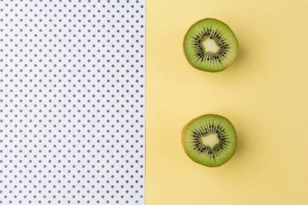 Pastel sarı ve puantiyeli arka plan üzerinde Yarım kesimli kivi.