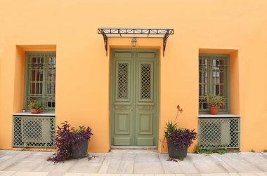Yunanistan 'ın Nafplio kentinde geleneksel renkli evler - turuncu duvar - yeşil kapı ve pencereler  