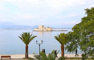 Bourtzi şatosu Argolis Yunanistan 'ın önündeki Nafplio limanında yürüyen insanlar