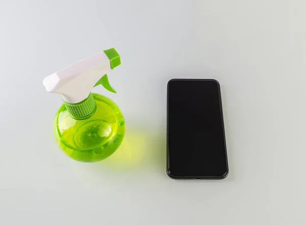 消毒喷雾器和一个黑色智能手机隔离在白色背景 防止住户清洁病虫害 — 图库照片